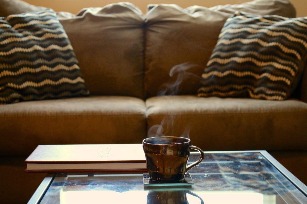 Brown leather sofa behind a coffee table with a steaming mug on top.