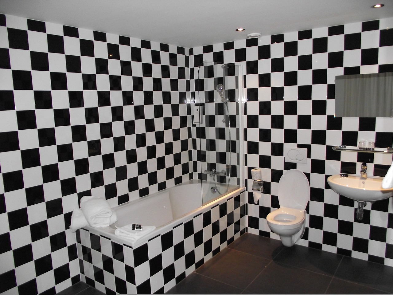 Black and white bathroom tiles with a shower, toilet, and sink.