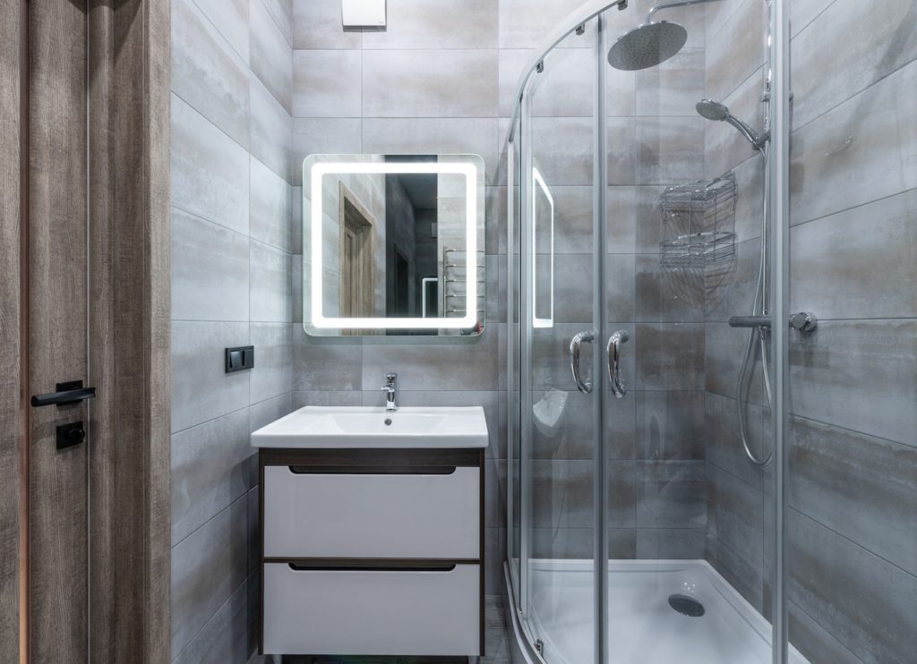 Standing shower, mirror, and counter in bathroom.